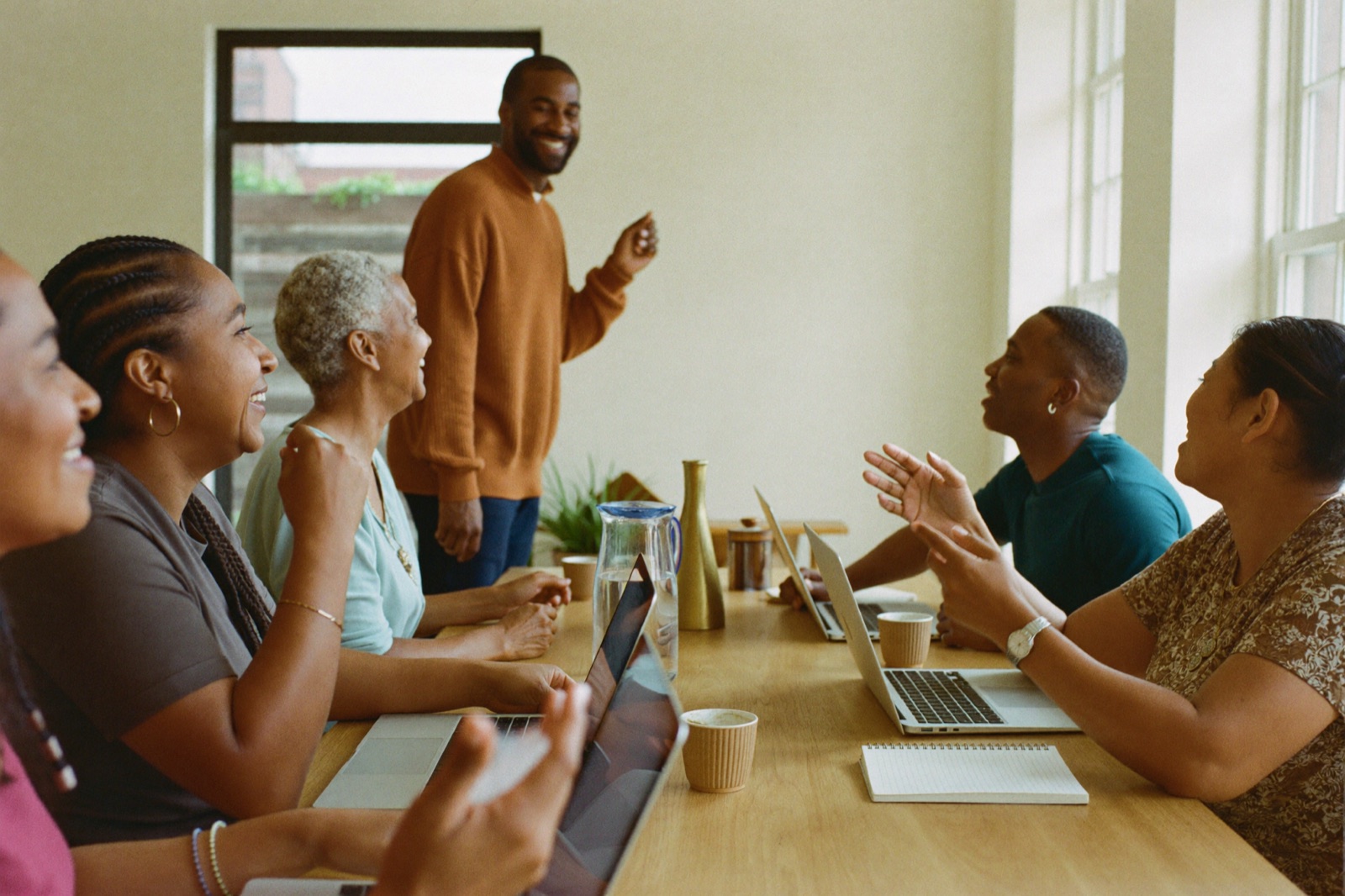 The community: operators around a table with laptops open, learning and laughing together